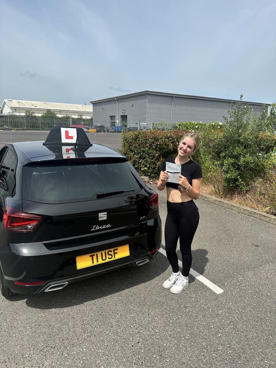 A TF Driving pupil beaming as she shows her pass certificate at the test centre